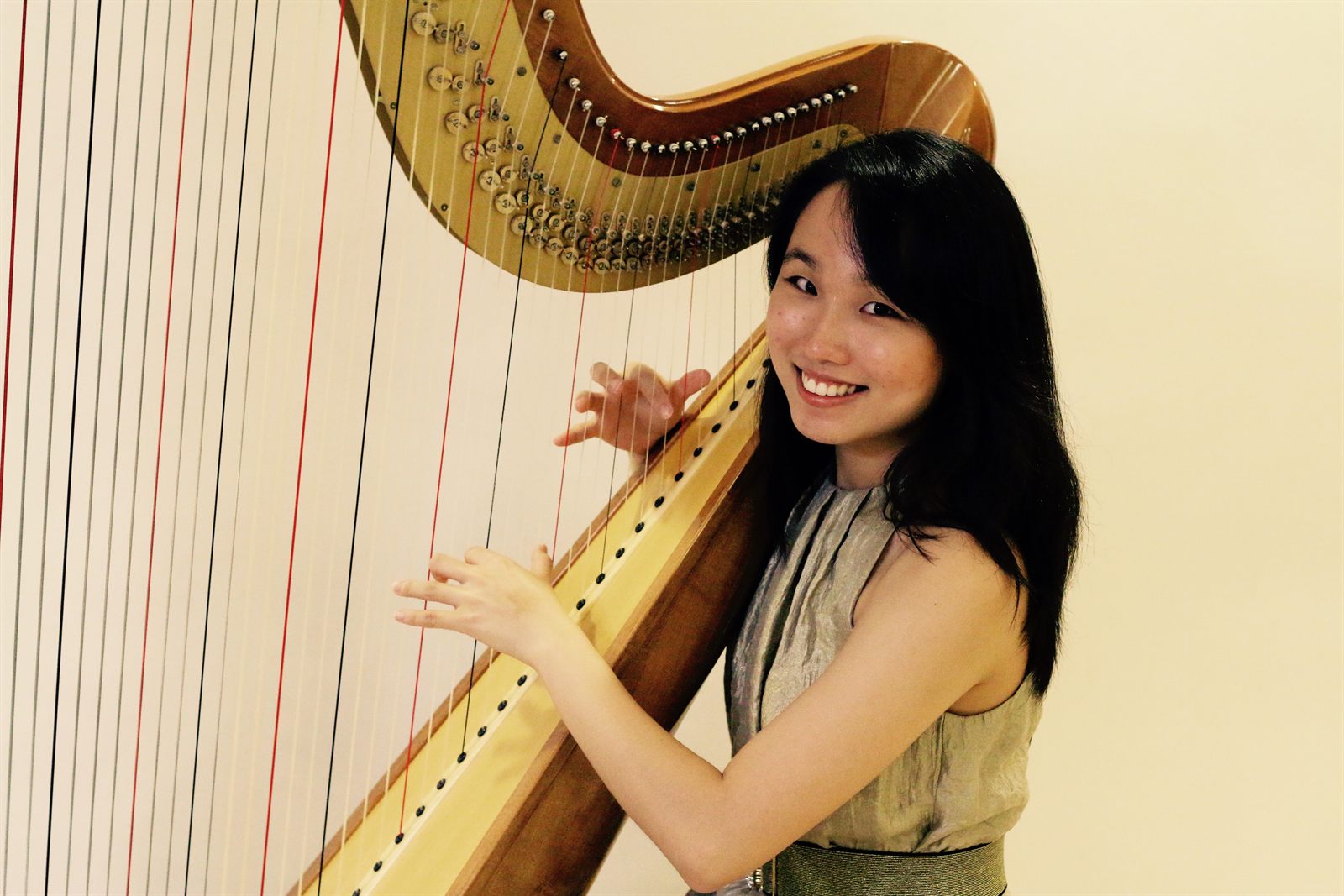Dora Lim smiling while playing the harp
